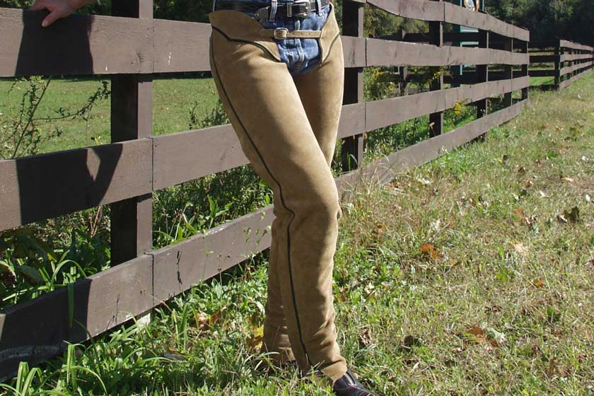 model wearing barnstable riding english schooling chaps sand color hunter stripe shes standing next to a wooden fence for horses